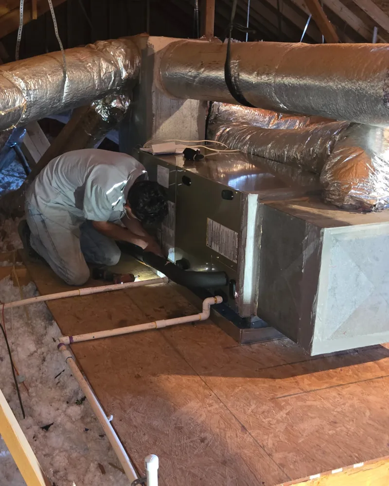 A Hawkins technician inspecting attic ductwork in an Abilene home