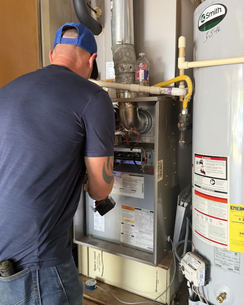 A Hawkins technician servicing a gas furnace in an Abilene home