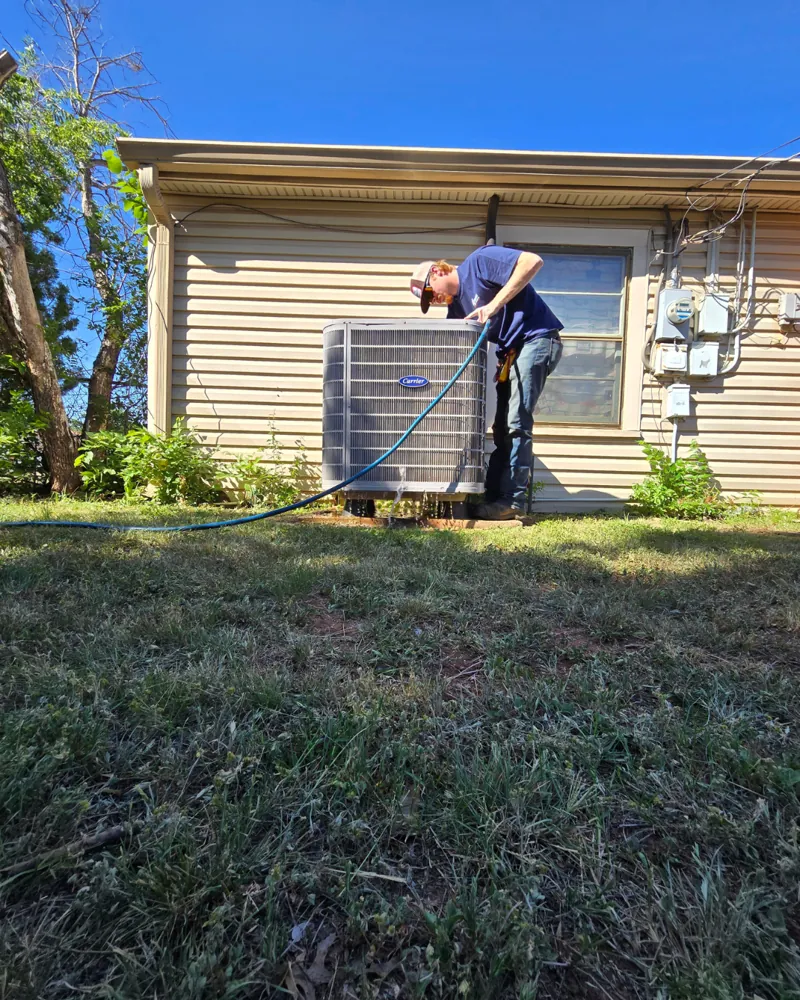Hawkins technician servicing an outdoor heat pump unit beside an Abilene home